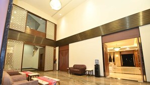 A spacious lobby with a marble floor, a sofa, a coffee table, and a decorative screen. - Hotel ShyamLeela - Khatushyamji (Shri Madhopur)