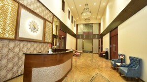A hotel lobby with a reception desk, seating area, and a chandelier. - Hotel ShyamLeela - Khatushyamji (Shri Madhopur)