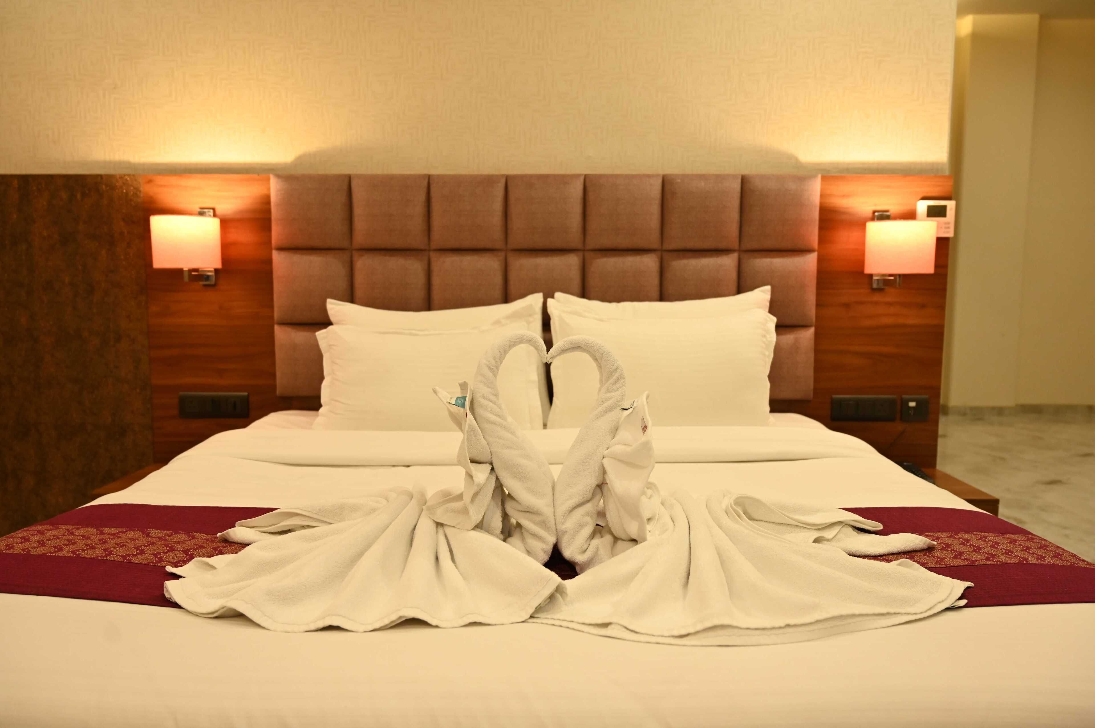 A hotel room with a large bed, two bedside lamps, and a wooden headboard.