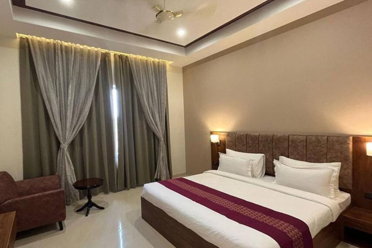 Une chambre d’hôtel avec un grand lit, une petite table, un canapé et des rideaux.