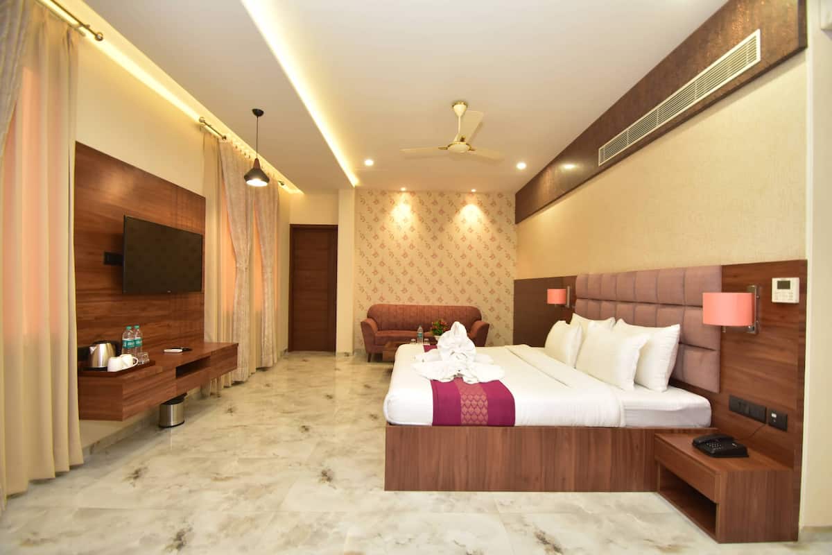 Une chambre d’hôtel équipée d’un lit, de tables de chevet, d’une télévision, d’un canapé et d’un ventilateur de plafond.