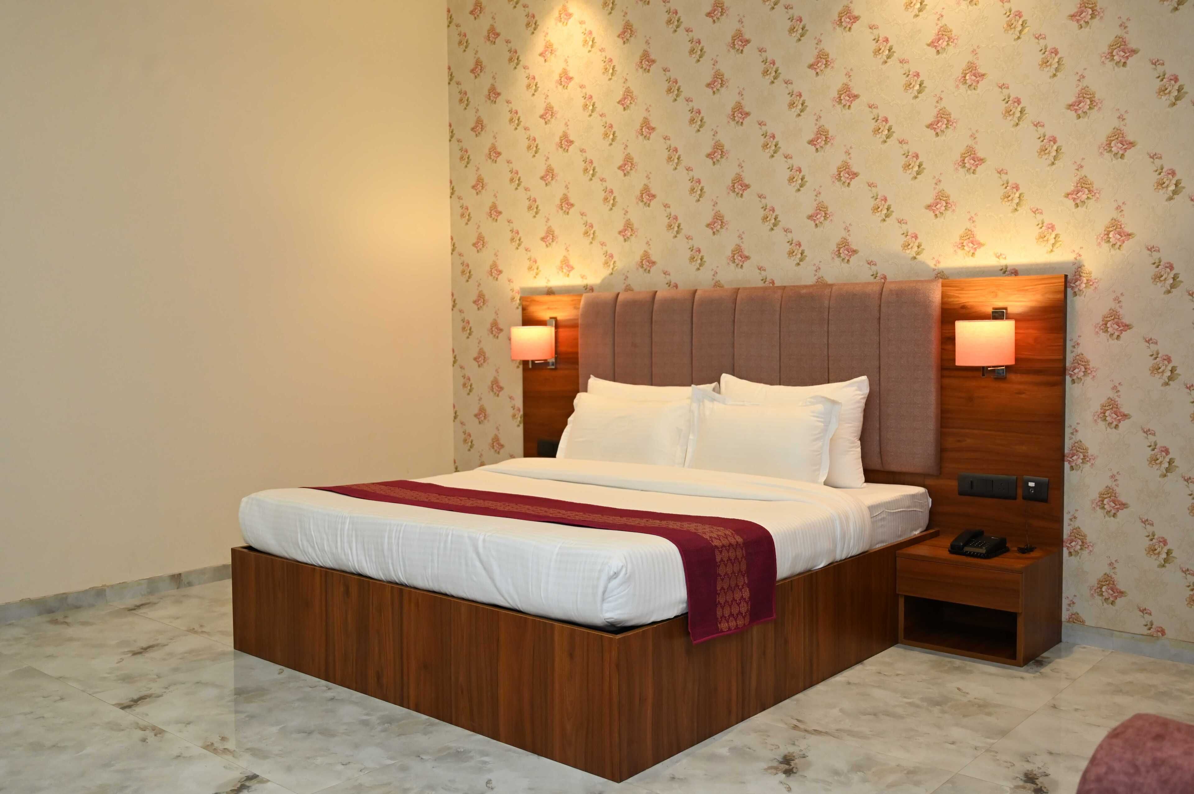 A neatly made bed with a wooden headboard, two bedside lamps, and a nightstand with a phone.