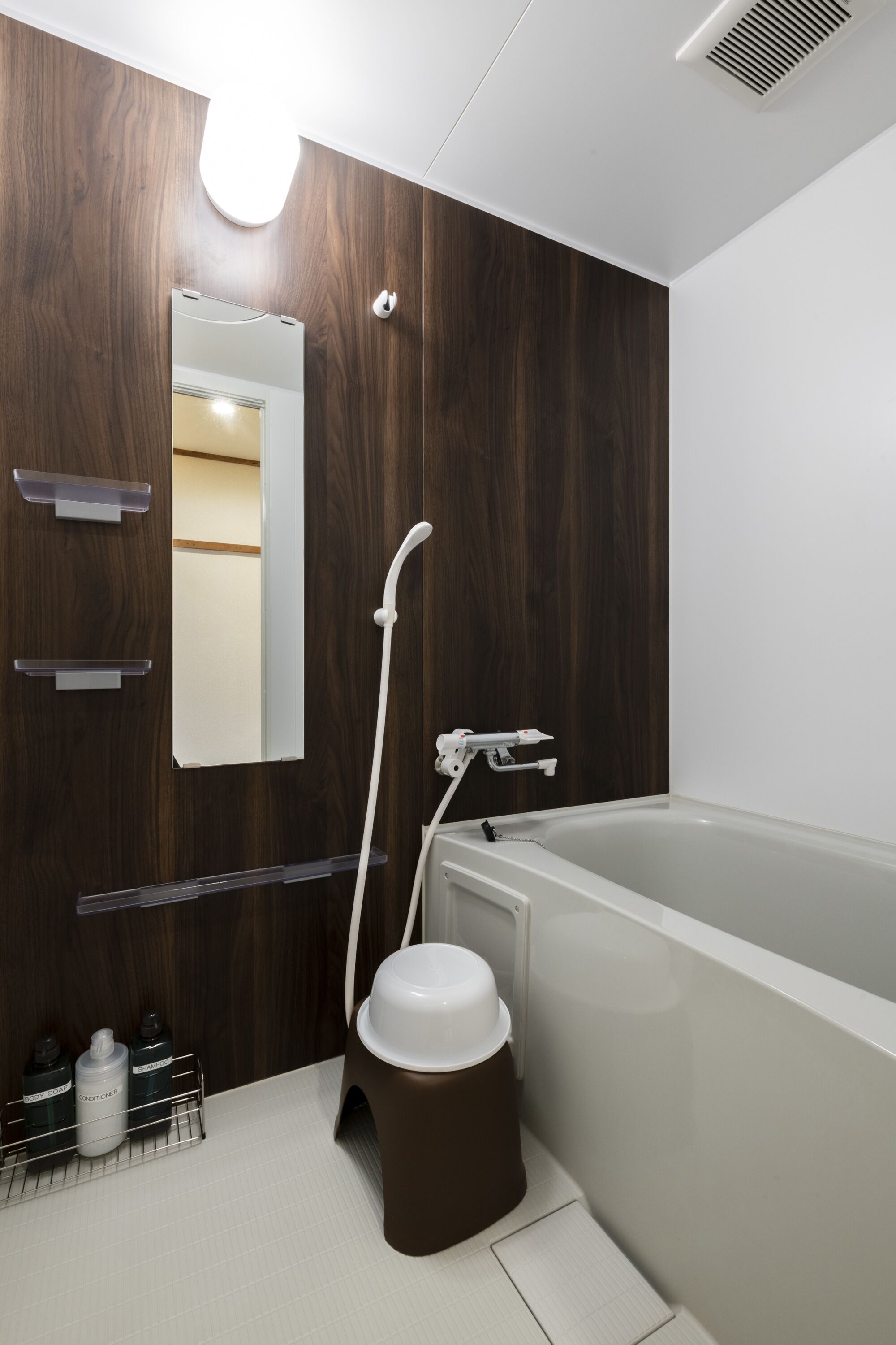 A modern bathroom with a wooden vanity, a large mirror, a bathtub, and a toilet.