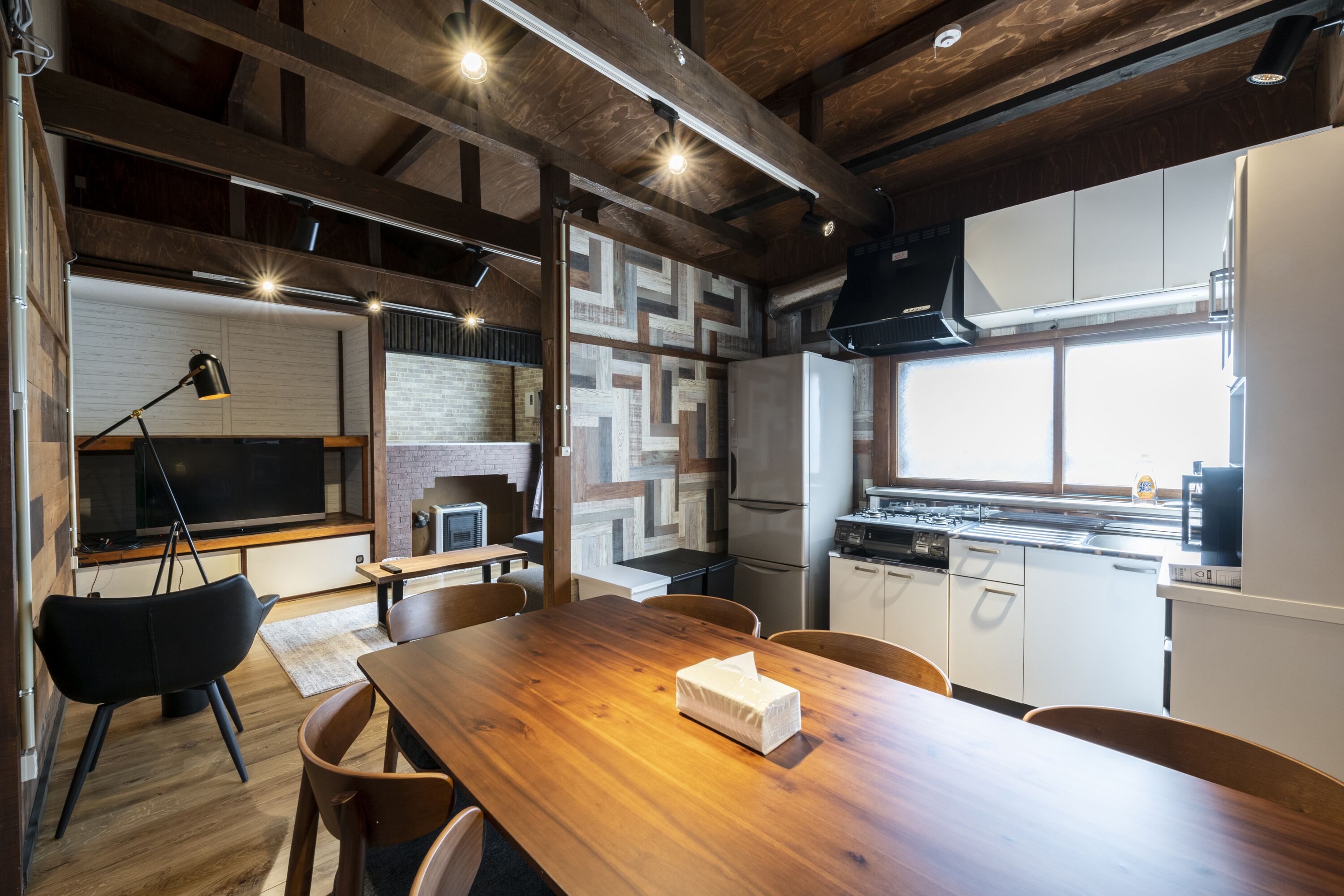A modern kitchen with wooden beams, a large wooden table, and a built-in oven.