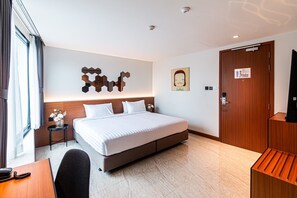 A modern hotel room with a large bed, a desk with a telephone, a small side table with a vase, a wooden wardrobe, and a wall-mounted artwork. - Frame Hotel Bangkok (Bangkok)