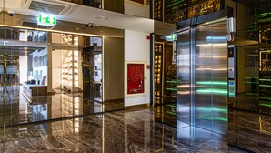 A modern hotel lobby with a shiny marble floor, a visible elevator, and a shoe store. - Frame Hotel Bangkok (Bangkok)