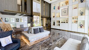 A spacious lobby with a modern sofa, a dark armchair, and a marble floor.