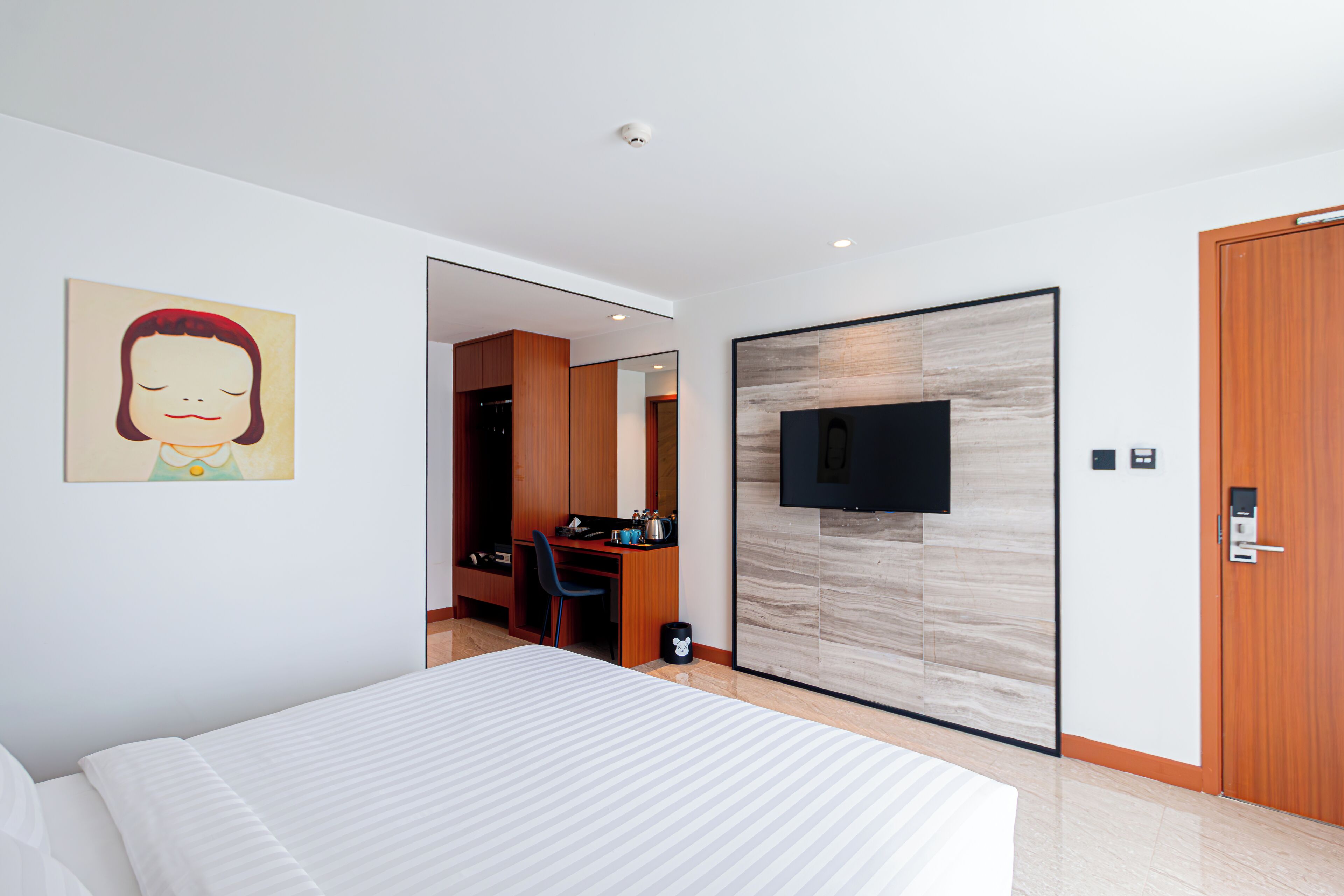 A modern hotel room with a bed, a desk, and a television.