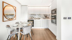Una cocina moderna con armarios blancos, encimera de mármol y horno empotrado.