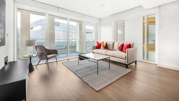 Una sala de estar moderna con un sofá, un sillón, una mesa de centro y una alfombra.