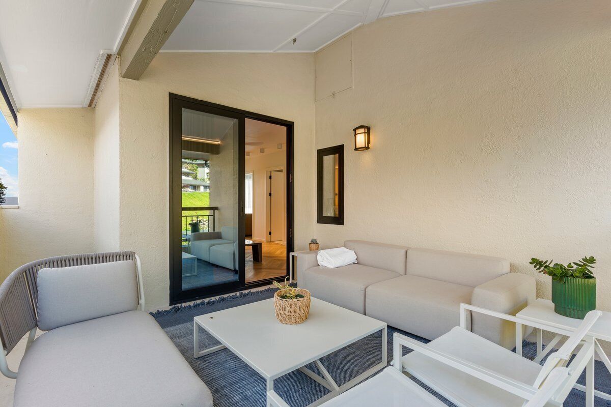 A modern outdoor seating area with a sofa, chairs, and a small table.
