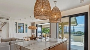 A modern kitchen with a marble island, wooden cabinets, and a dining area with a table and chairs.