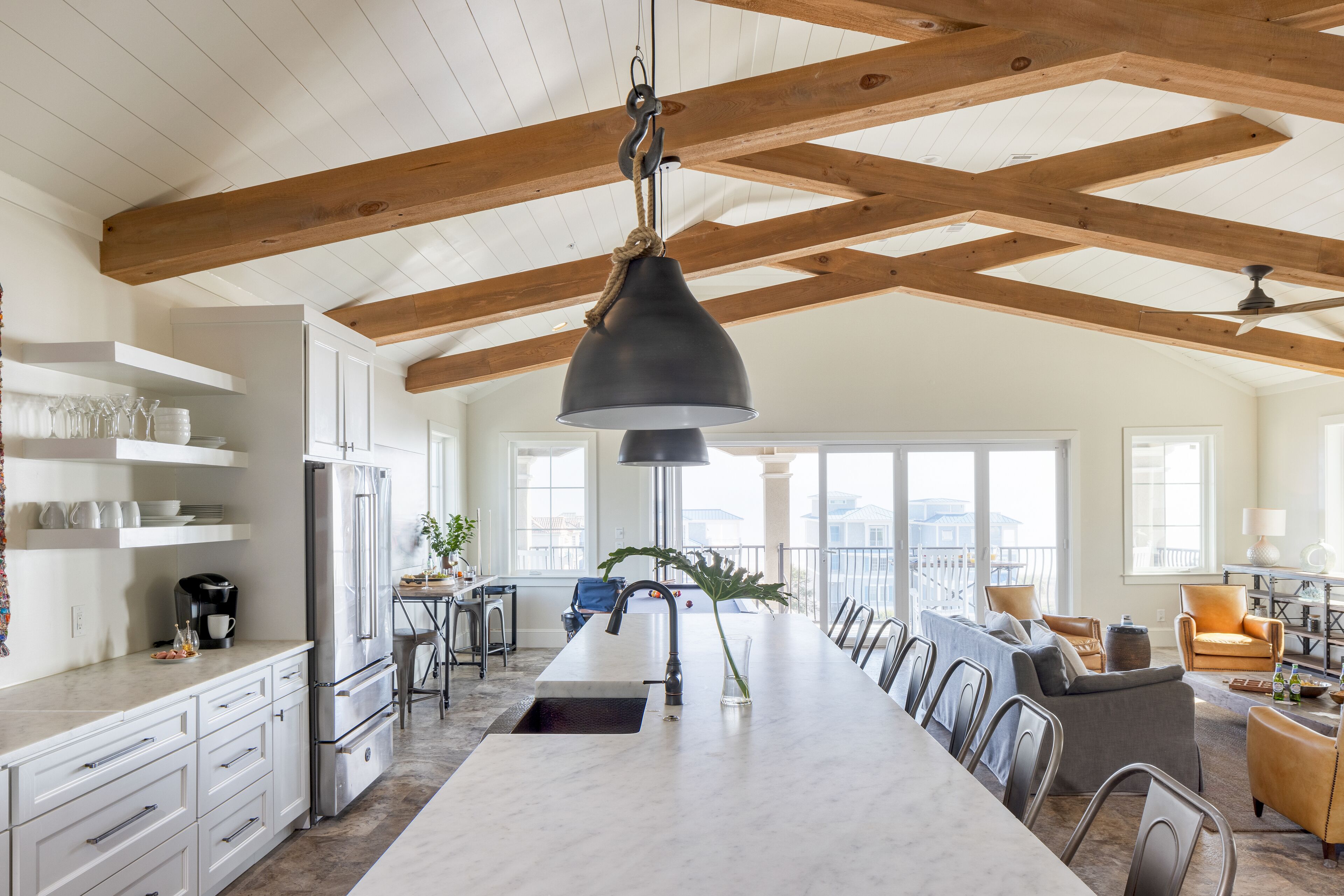 A spacious kitchen with a long island, white cabinetry, and a hanging pendant light.