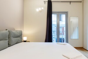 A hotel room with a bed, a nightstand with a lamp, a window with curtains, and a view of a balcony. - Vista Arco della pace CASTELLO SFORZESCO (Milan)