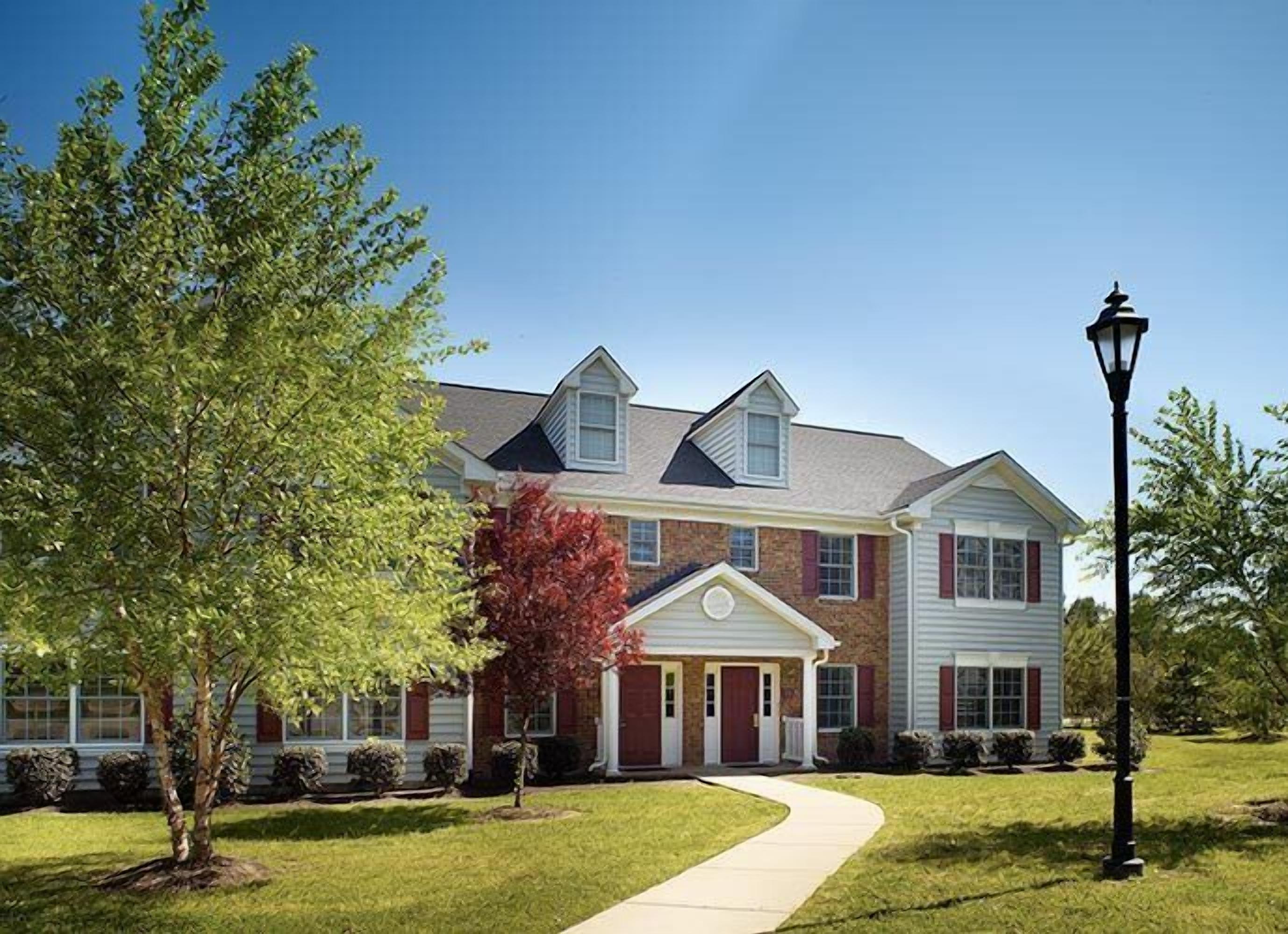 A two-story house with a brick facade, a front porch, and a well-maintained lawn.