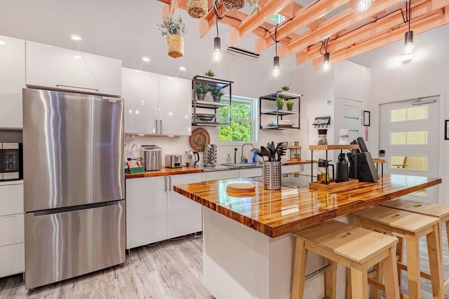 A modern kitchen with a stainless steel refrigerator, wooden countertops, and a central island with stools.