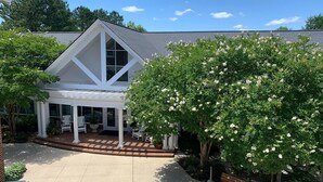 A modern house with a covered porch, a large tree with white flowers, and a well-maintained garden.