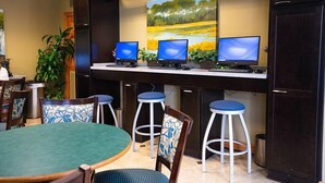 A reception area with a desk, three monitors, and a painting of a landscape.