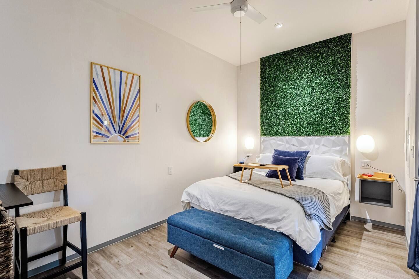 Een moderne slaapkamer met een bed, een stoel, een klein tafeltje en een wandlamp.