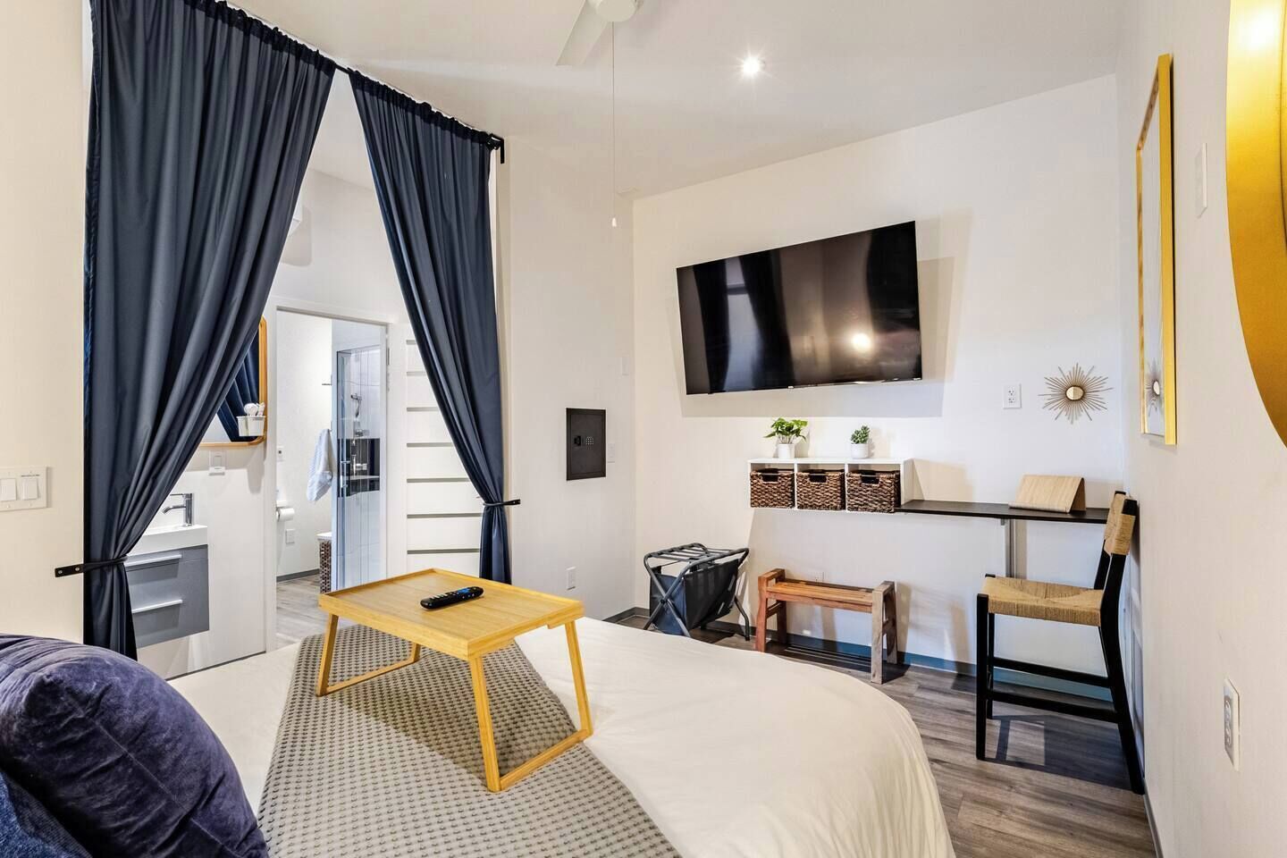 A modern hotel room with a bed, a TV, a desk, and a chair.