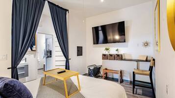 A modern hotel room with a bed, a TV, a desk, and a chair.