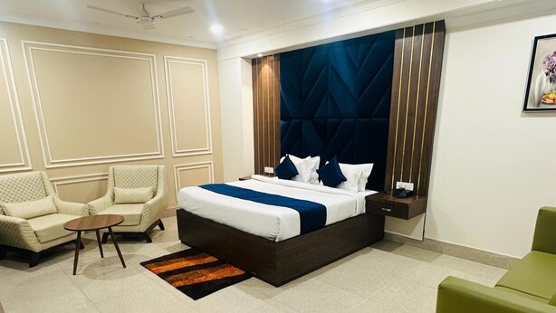 Una habitación de hotel con una cama grande, un sofá, una mesita y una mesita de noche.
