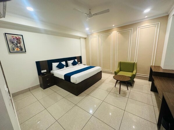 A bedroom with a bed, a chair, a desk, and a wardrobe.