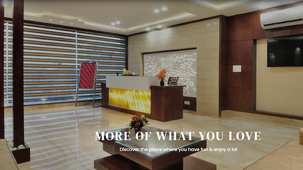 A modern reception area with a reception desk, a large screen, and a seating area with sofas. - Hotel Fortune Ganga (Haridwar)