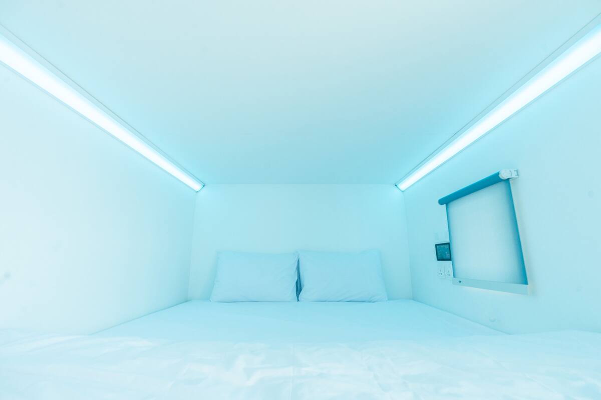 A room with a bed, a bedside table, and a wall-mounted TV.