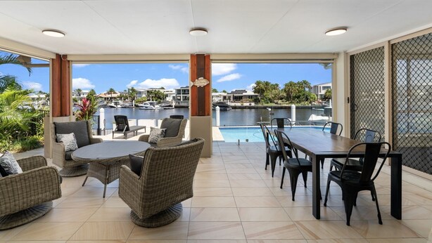 A covered outdoor area with wicker furniture, a pool table, and a view of a marina. - Bribie Bliss: Luxe Canal Living (BANKSIA BEACH)