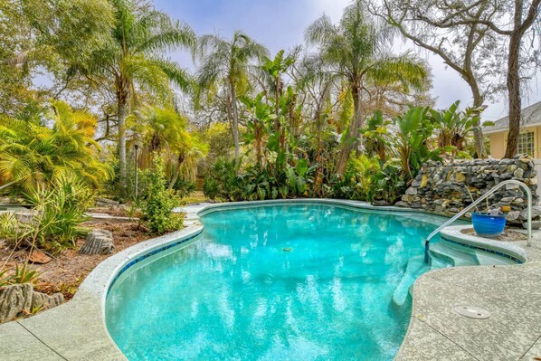 A swimming pool surrounded by tropical plants and a stone wall. - Private Pool, Backyard Oasis, 10 Minute Walk to Beach, 3 Minute Walk to River, $300 in Free Tickets! (St. Augustine)