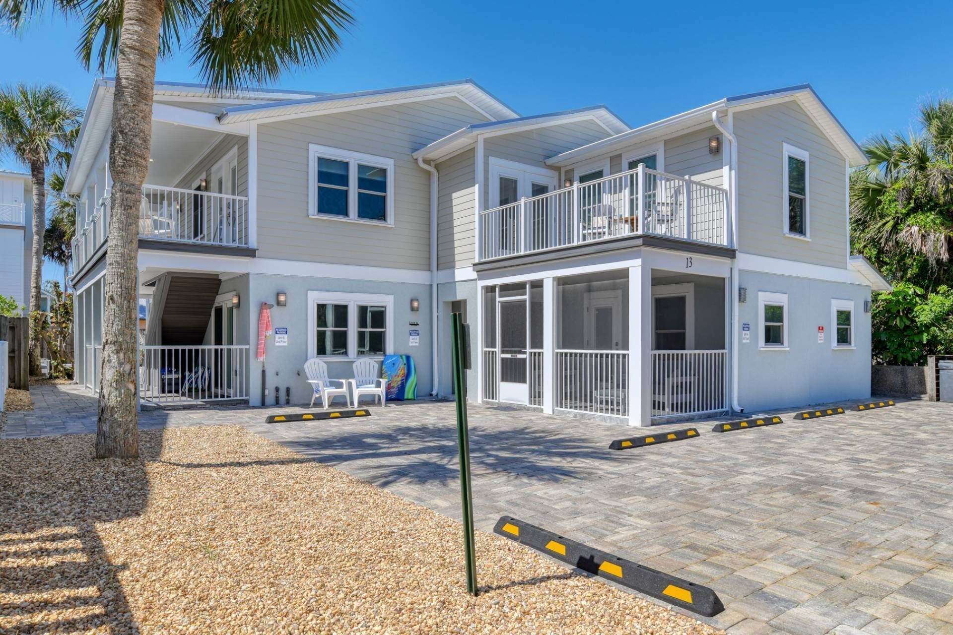A two-story building with a balcony on the upper floor, a covered entrance, and a paved driveway with bollards.