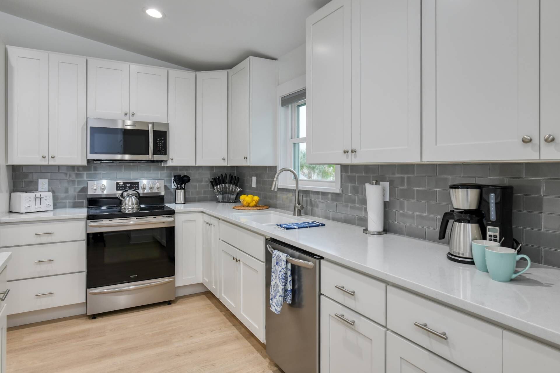 A modern kitchen with white cabinets, stainless steel appliances, and a light-colored countertop.