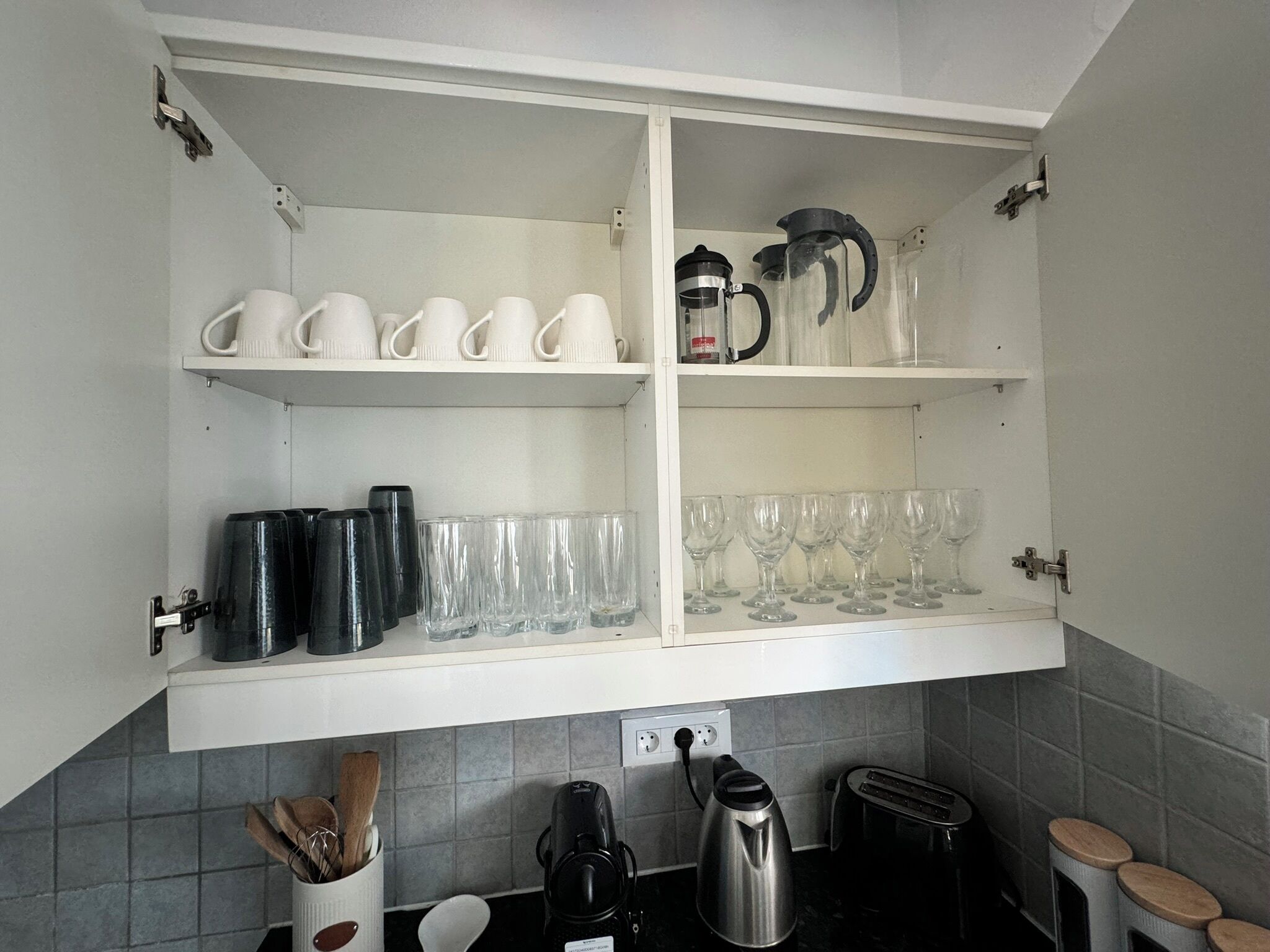 Una cocina con armarios blancos, una cafetera, un hervidor y un tostador.