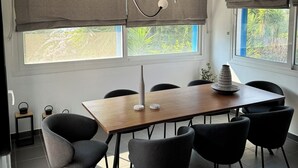 A modern dining area with a wooden table, six chairs, and a pendant light fixture.