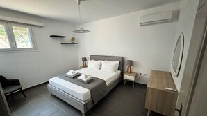 Un dormitorio moderno con cama, mesitas de noche, una silla y un escritorio.