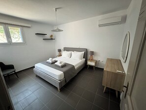 Un dormitorio moderno con cama, mesitas de noche, una silla y un escritorio.
