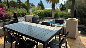 Un patio al aire libre con mesa y sillas, una piscina y vistas a las montañas.