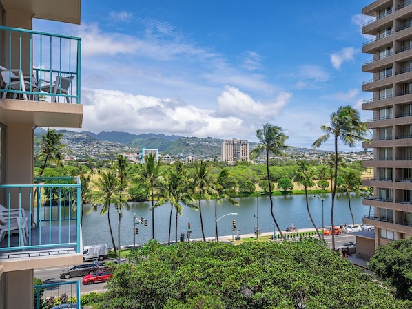 A hotel with a view of a lake, palm trees, and a cityscape in the background.