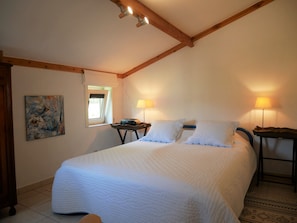 A bedroom with a large bed, two bedside lamps, a painting on the wall, and a window with a view. - Nova Park V43 - Charming fisherman's cottage with large fenced garden. (De Haan)