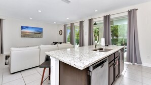 A modern kitchen with a granite countertop, stainless steel appliances, and a large window with curtains. - Cheerful Home near Disney with Private Pool, Themed Rooms and Waterpark &. (Kissimmee)