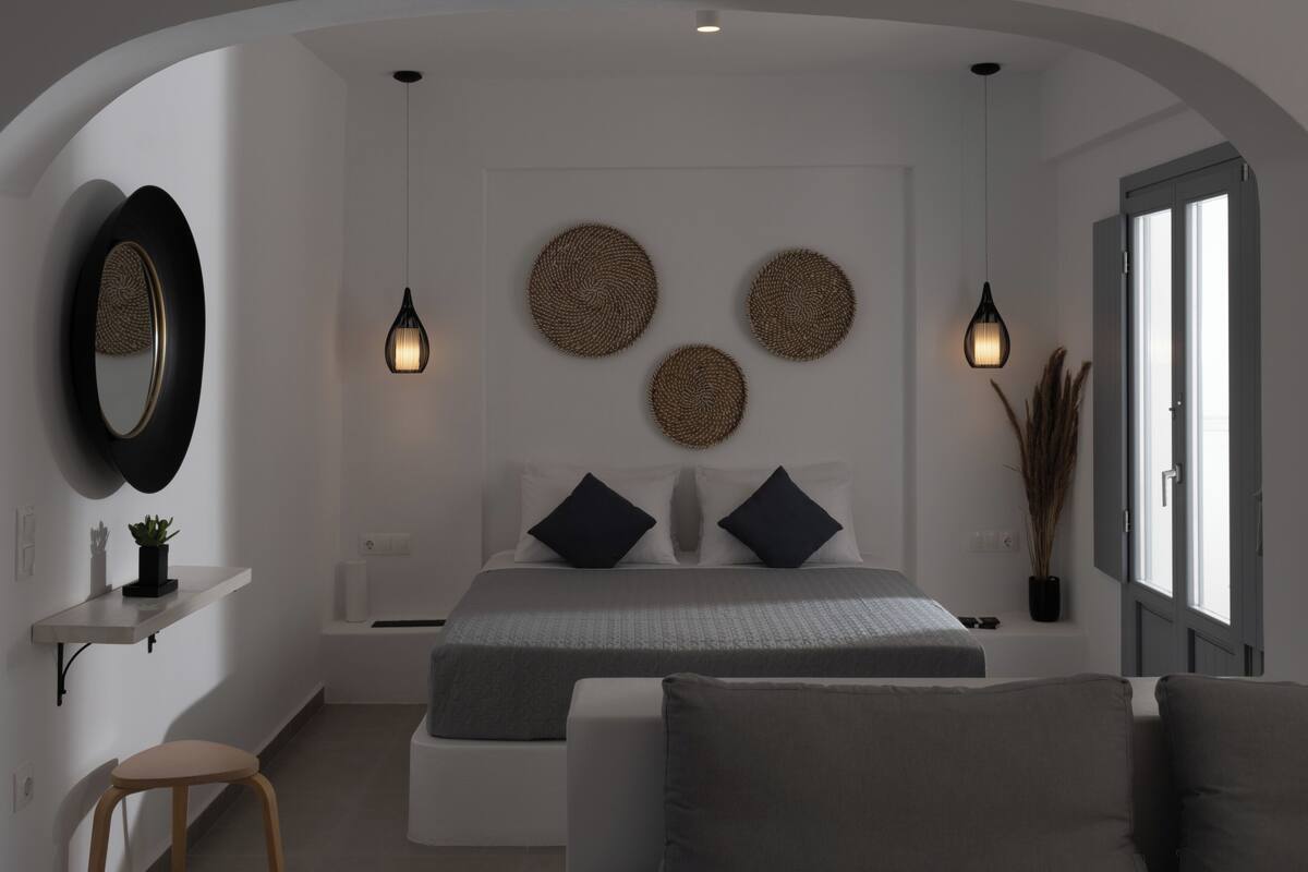 Un dormitorio moderno con cama, mesitas de noche y un ventanal grande.