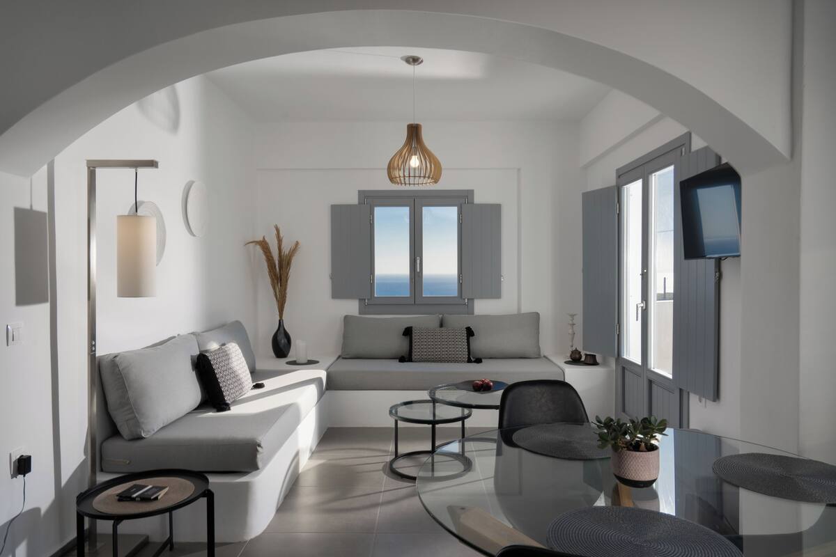 Una sala de estar moderna con un sofá, una mesa de centro, un televisor y un ventanal con vistas.