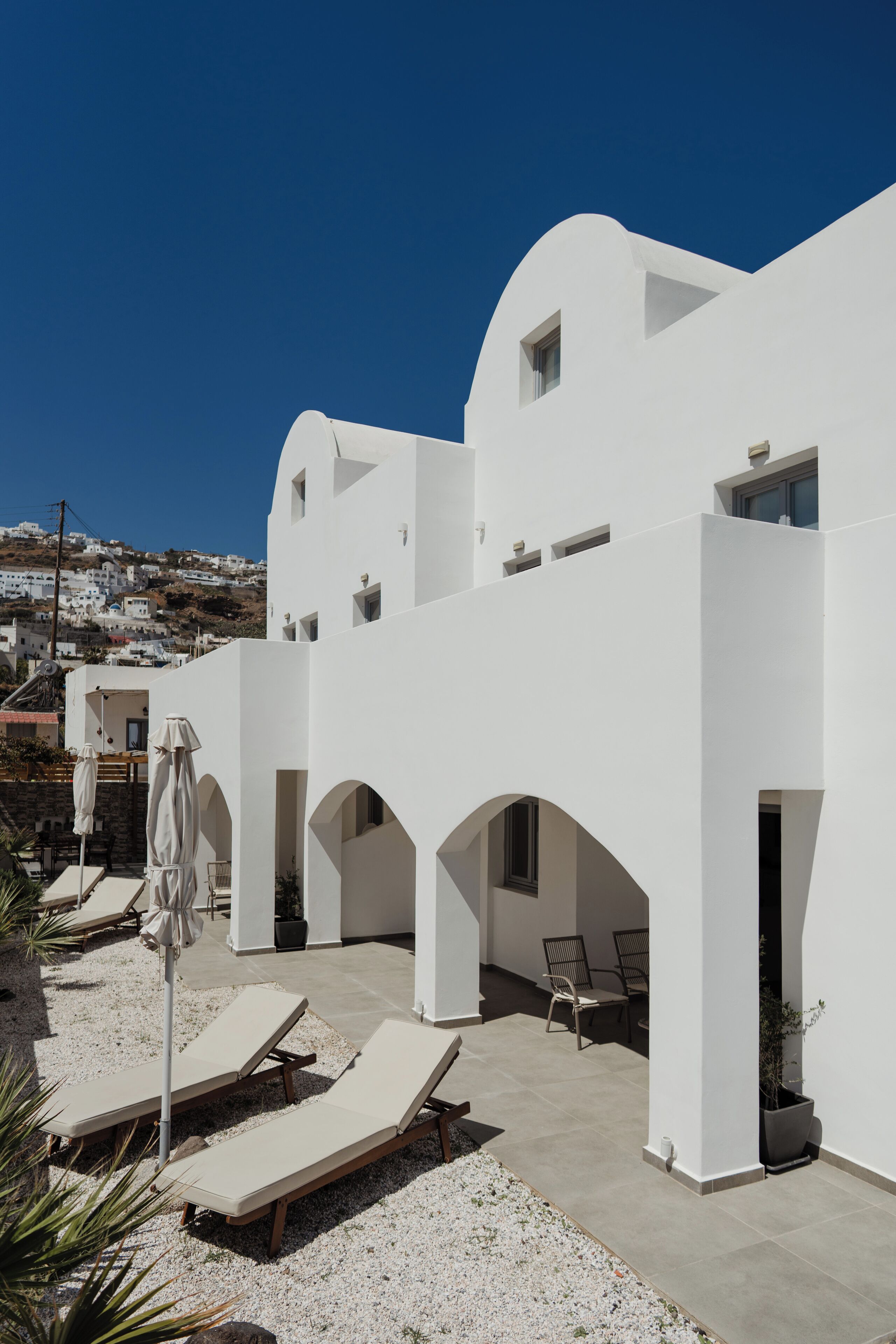 Un bâtiment blanc doté d’une cour intérieure, d’un espace extérieur aménagé pour s’asseoir et offrant une vue sur les environs.