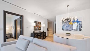 A modern living room with a sofa, a round coffee table, and a chandelier. - Solaris PHCE - 2 Bedroom (Vail)