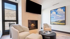 A modern living room with a fireplace, comfortable seating, and a large window. - Solaris PHCE - 2 Bedroom (Vail)