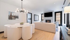 A modern living room with a white sofa, a round coffee table, and a fireplace. - Solaris PHCE - 2 Bedroom (Vail)