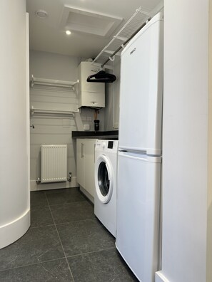 Une cuisine compacte équipée d’un lave-linge intégré, d’un réfrigérateur et d’un radiateur.