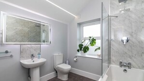 Un baño moderno con lavamanos, inodoro y bañera de mármol.