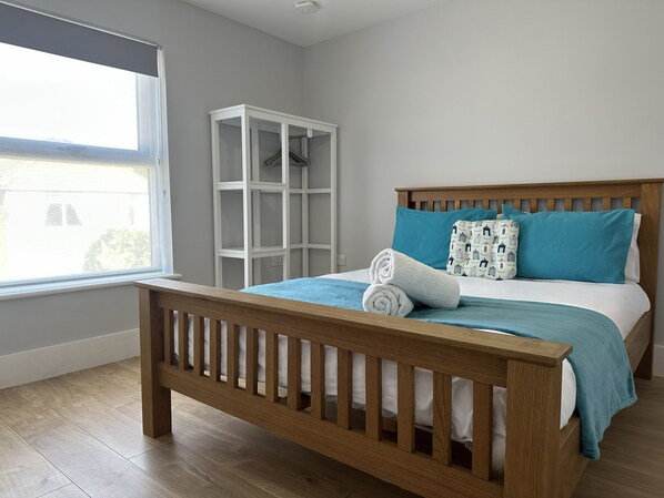 A bedroom with a wooden bed, a window, and a white shelving unit.